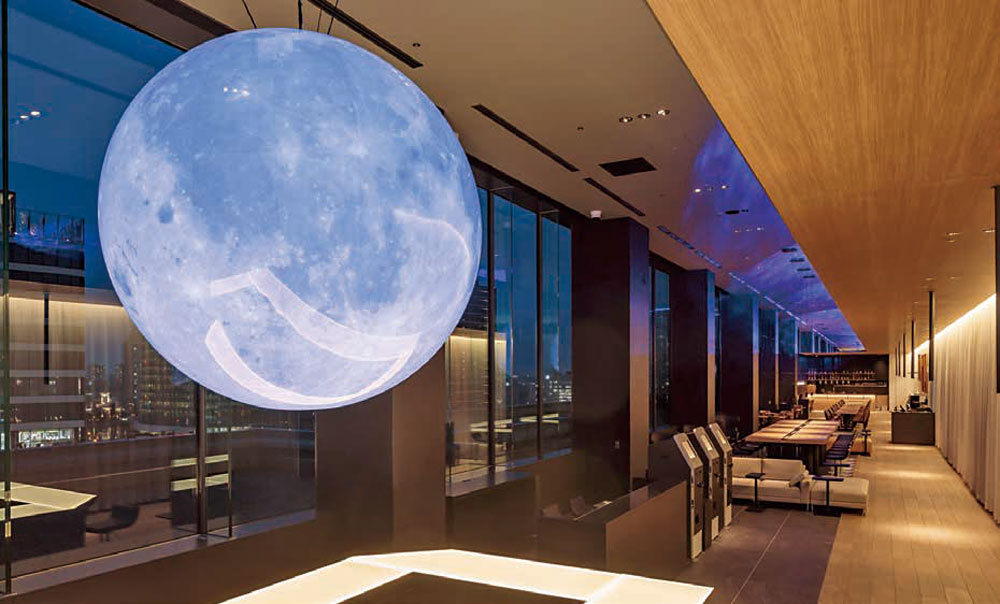 みなとみらいの近未来的なイメージを具現化した月のオブジェの照明が印象的なロビー。天井が高く、ロビー、コワーキ ングスペース、レストランが一体となった開放的な空間。自動チェックイン機も備える。