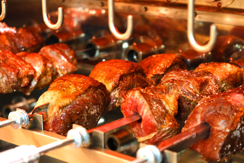 特製シュラスコマシーンで焼かれる塊肉。シュラスコは20種類のラインナップが用意されており、昼夜問わず楽しむことができる 