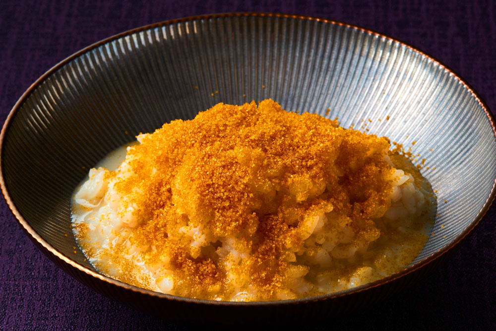 「キノコ雑炊カラスミ添え」。キノコ鍋の〆に提供される一品。キノコの滋味が溶け出したスープと北海道産の“ななつぼし”で作った雑炊に、カラスミパウダーの風味が深みを与えている