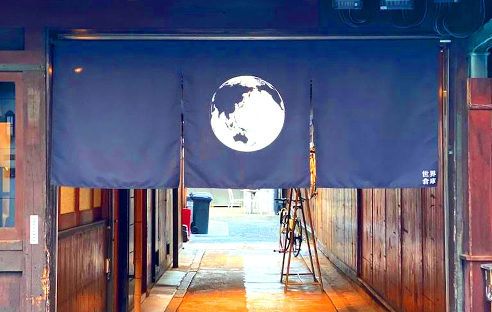 「世界倉庫」外観。地球がデザインされた暖簾のむこうに、ネオとニュー、もっとも“インな京都”が待っている   
