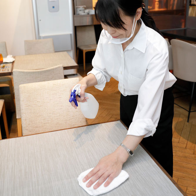 取り出した微酸性電解水でテーブルを拭くスタッフ