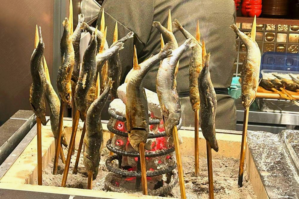 ‟大トロ鰯原始焼き“。鰯のみならず、カウンター内に設えられた炭火のまわりに食材を配し火入れする‟原始焼き”。遠火でじっくり焼き上げることで外はパリッと、中はふっくらと焼くことができ、風味よく仕上げることができる