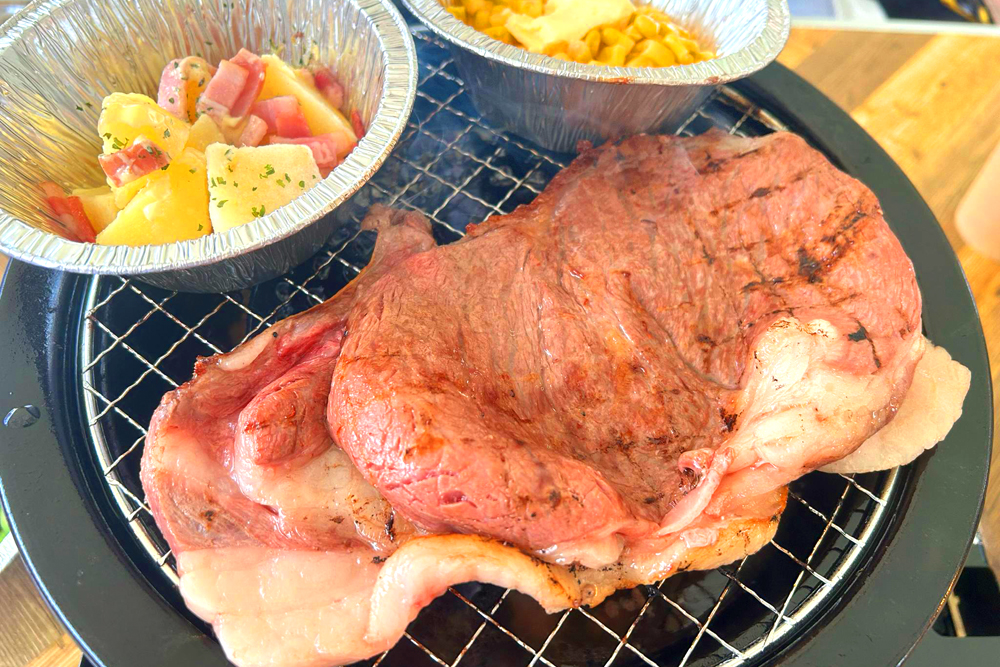 ‟豪華BBQと屋台食べ放題コース“から、メインの和牛ロースステーキ、ジャーマンポテトとコーンバター。同ビアガーデンには多々魅力があるが、食材の良さや味わいの良さもそのひとつだ