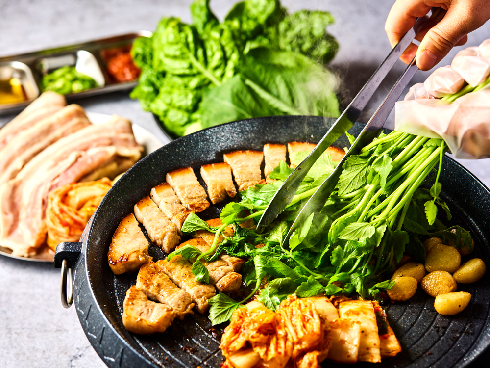 様々な具材を鍋に盛り付け、スープを注いで卓上で煮込みながら味わう韓国の鍋料理“ジョンゴル”。メニューは‟サムギョプル“と‟チュクミ・ムギョプル”から選べ、どちらもシンプルなものに加えて、ミナリ（セリ）付きのメニューが用意されているのも嬉しいポイントだ