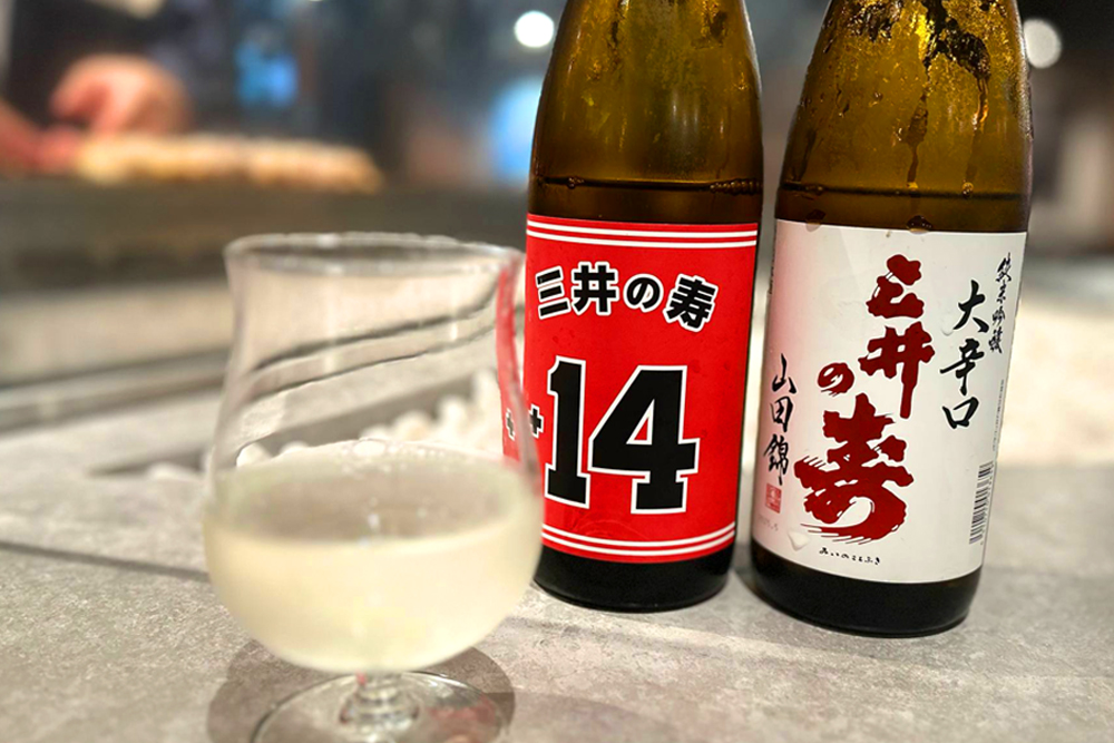 ドリンクメニューも各種こだわりの銘柄を揃えているが、特に日本酒のラインナップが豊富で、中には日本酒カクテルも用意されている。写真は、1本に2つのエチケットが貼られている‟三井の寿 純米吟醸“。赤い面はスラムダンクバージョンだ