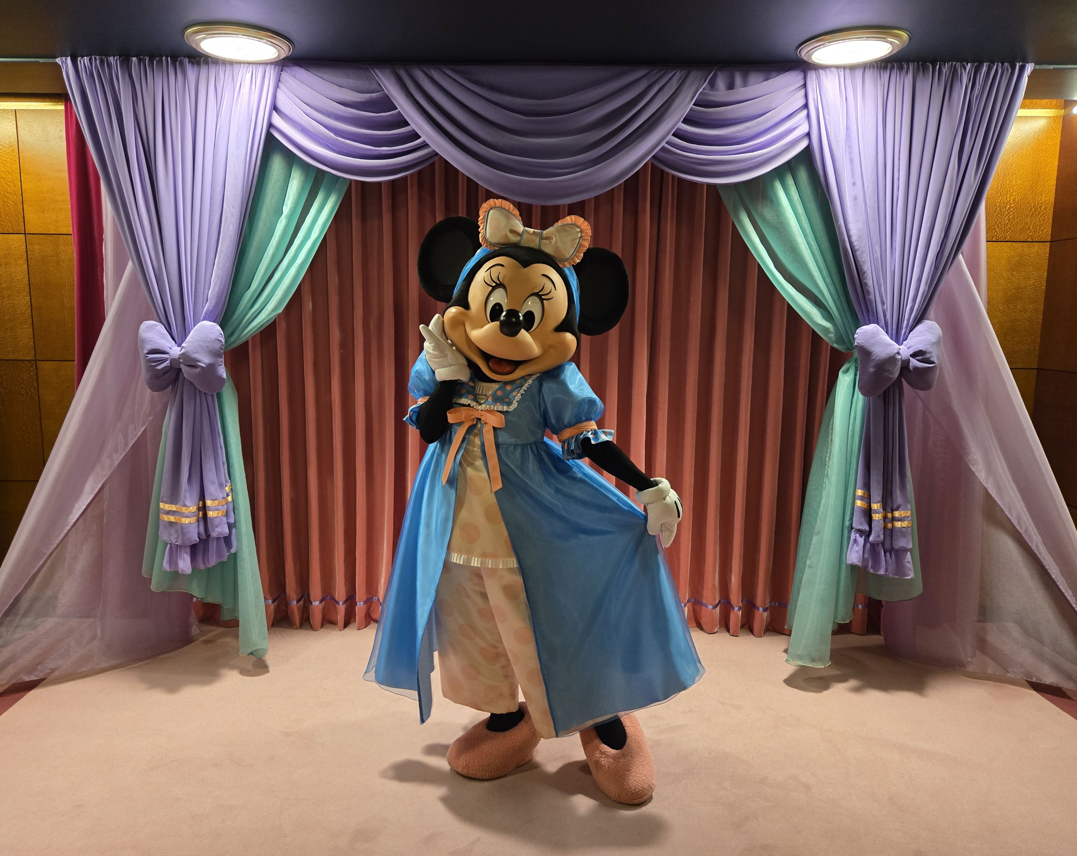 カラフルなカーテンやラグが施されたアンバサダーラウンジにて、パステルカラーで彩られたパジャマを身にまとったミニーマウス