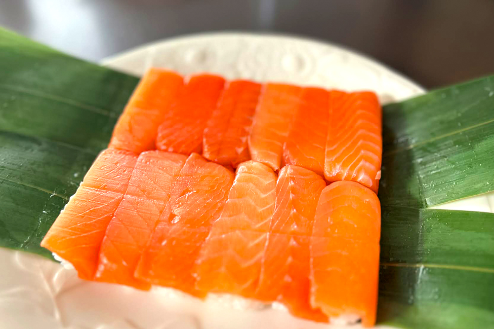 同店およびグループ会社が運営する通販サイト「順風屋」で購入できる、“手割り 鱒のすし”。鱒の脂と旨味、そして酢のバランスに、従来の‟ます寿し“とは違う、生感のある味わいを体験できる一品。切らずに手で割って食べられる“手割り”のスタイルは特許を取得している