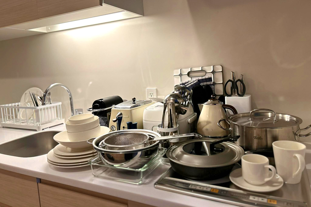 客室に設えられたキッチンウェア（※一部）。トースターや炊飯器、鍋類に加え、家庭用冷蔵庫や電子レンジ（※写真外）も備える。クリスタル製のフルートとワイン用グラス2種も用意されている。施設1階には「LINCOS」があり、タワマンライフさながらの滞在を楽しむお客さまも多い