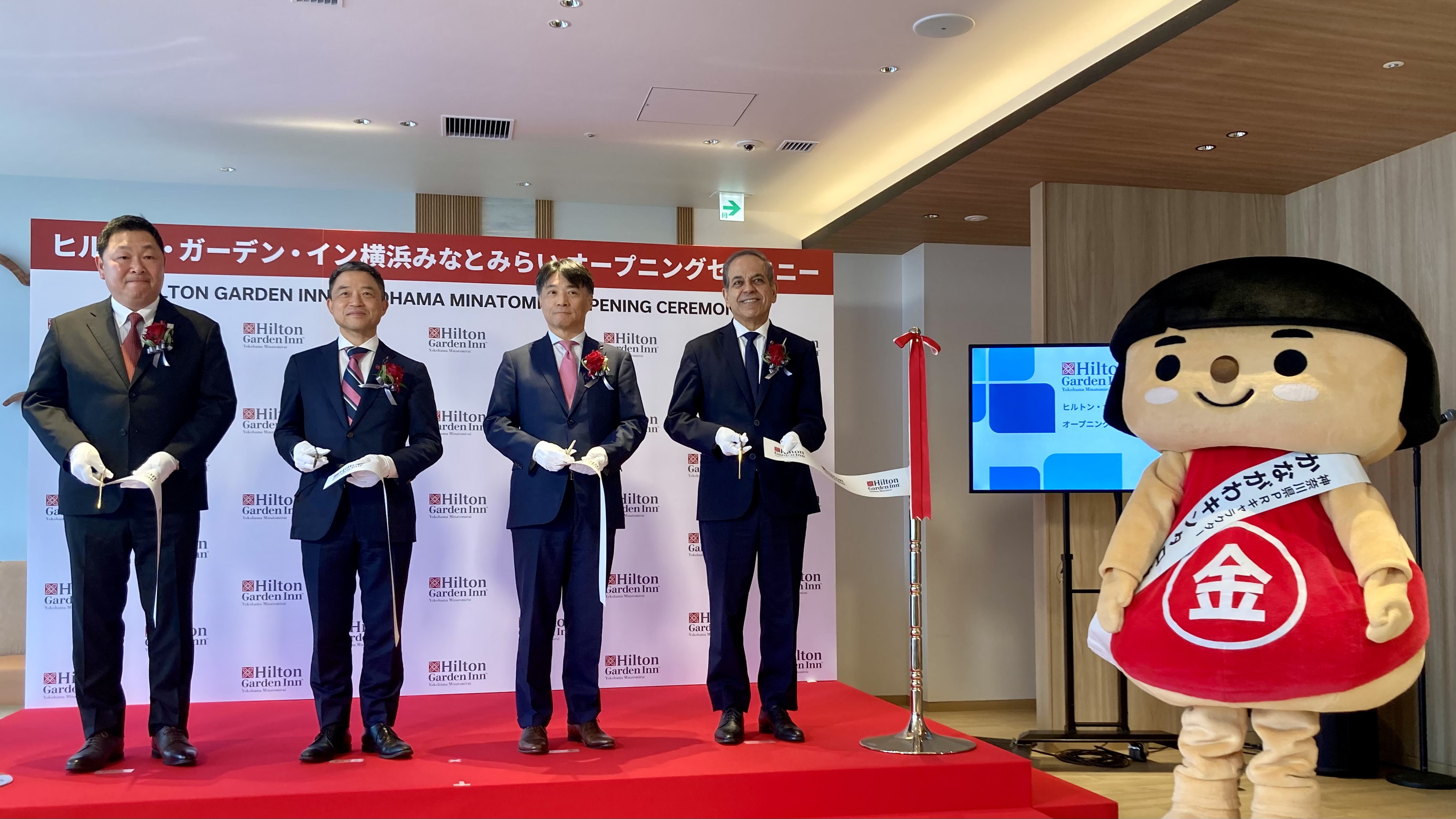 左から、ヒルトン・ガーデン・イン横浜みなとみらい 総支配人 川合 肇氏、三菱ＨＣキャピタルリアルティ㈱代表取締役社長 若尾逸男氏、三菱ＨＣキャピタル㈱代表取締役 副社長執行役員 松永愛一郎氏、ヒルトン 日本・韓国・ミクロネシア地区代表 ジョセフ・カイララ氏。神奈川県の公式PRキャラクター「かながわキンタロウ」も開業セレモニーに参加